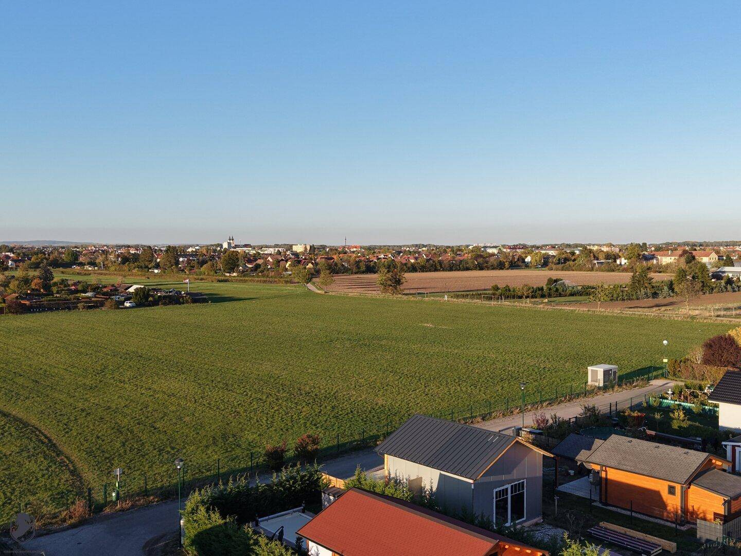 Ausgedehnte grüne Felder mit einer kleinen Stadt in der Ferne unter klarem Himmel.