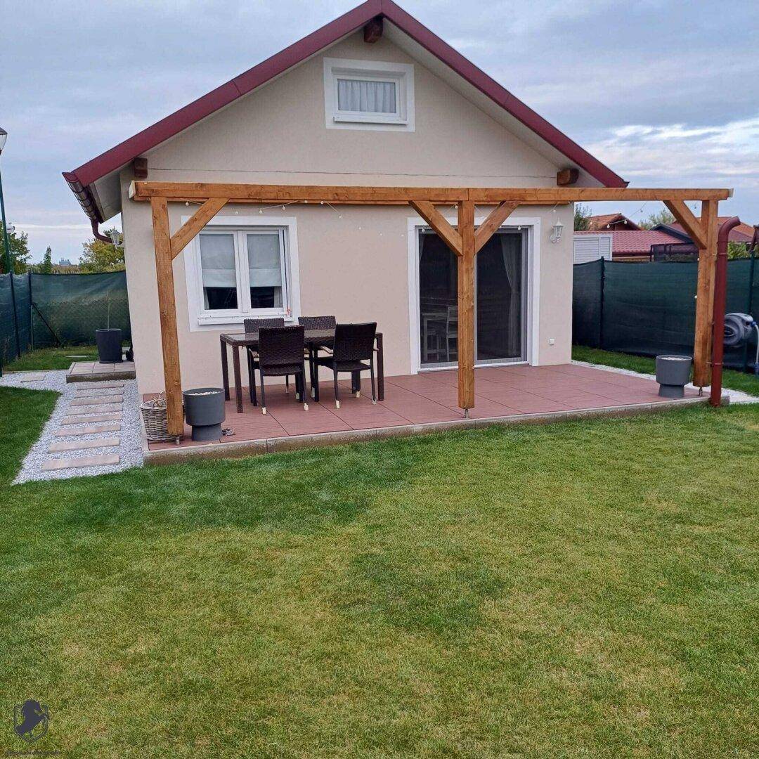 Möblierte Terrasse mit Holzdach und Esstisch, direkt am Haus gelegen.