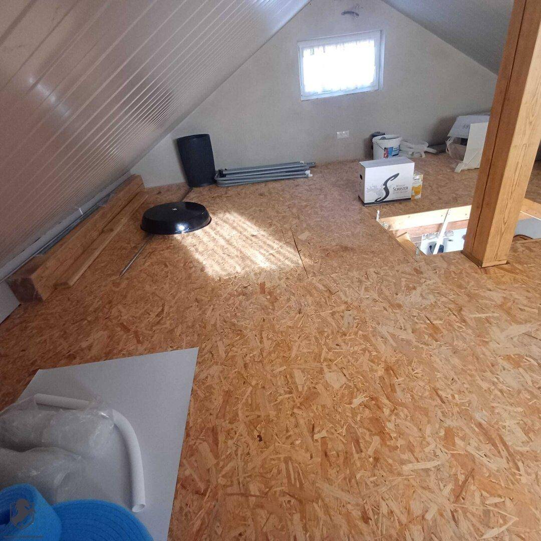 Unfertiger Dachboden mit OSB-Plattenboden und sichtbaren Dachschrägen.