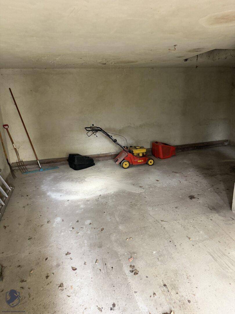 Unfertiger Abstellraum mit Betonboden, Gartengeräten und einer Leiter.