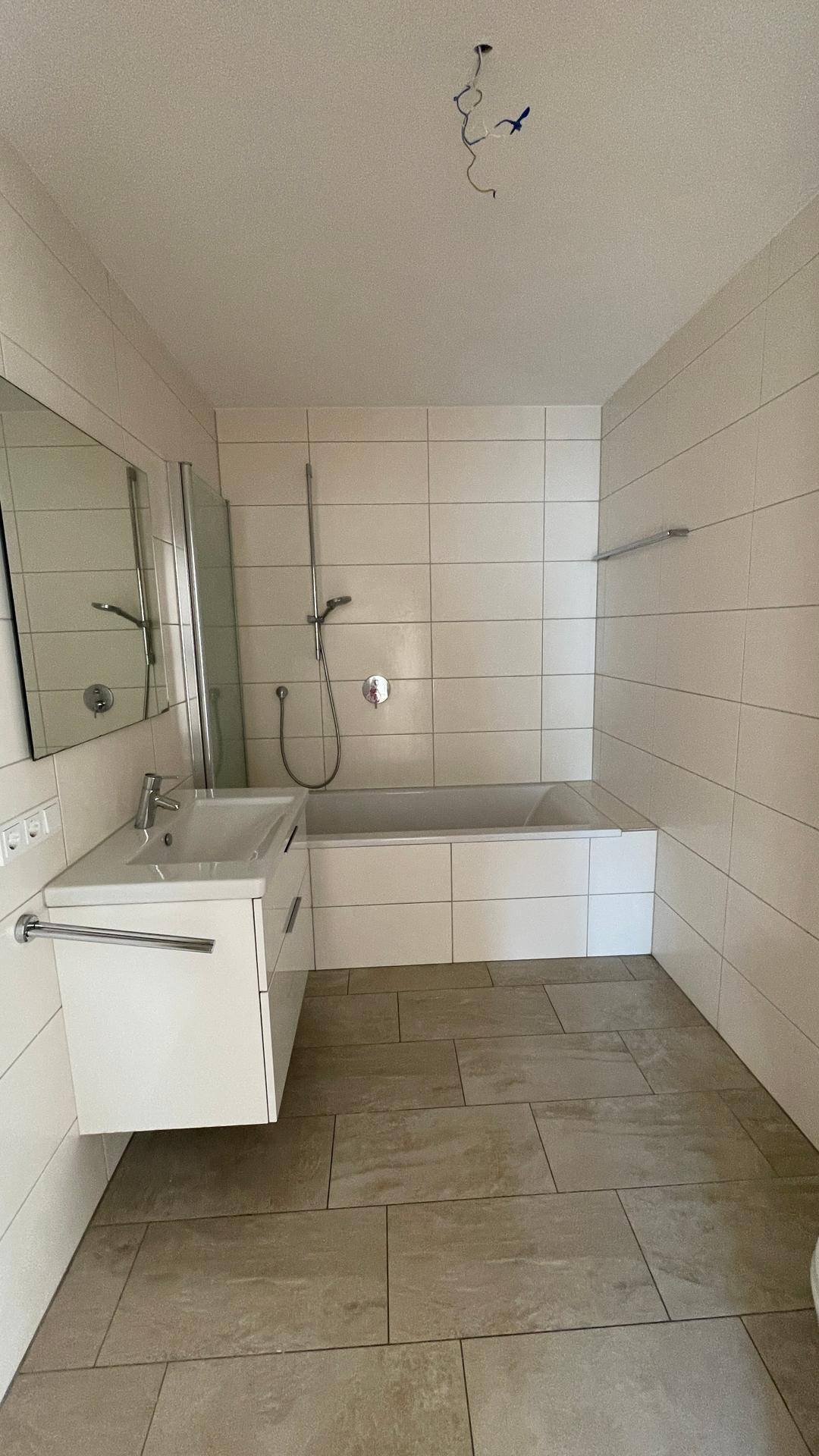 Modernes Badezimmer mit Badewanne, Duschbereich und schwebendem Waschtisch.