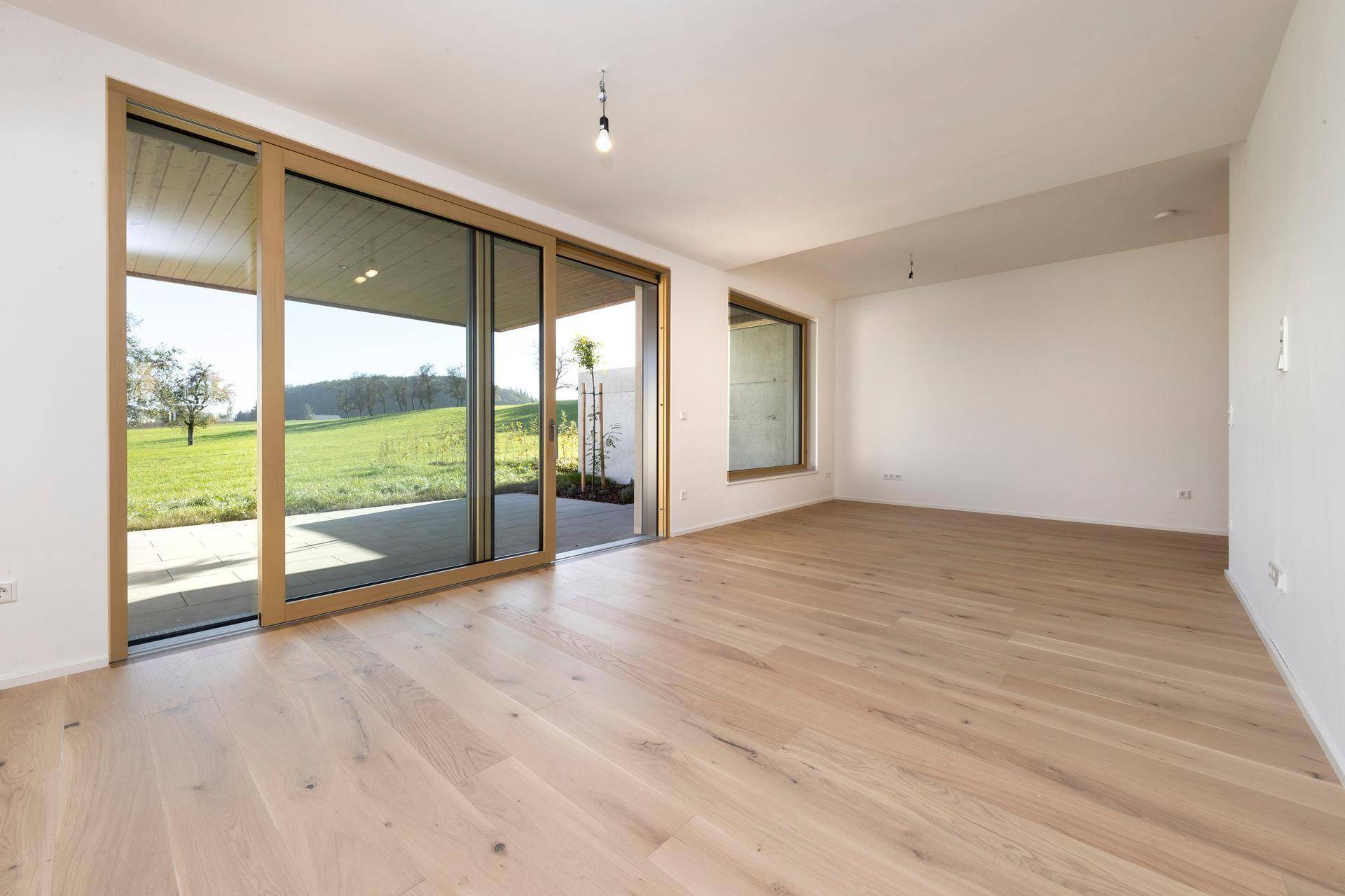 Heller Wohnbereich mit Holzboden und großem Zugang zur Terrasse.