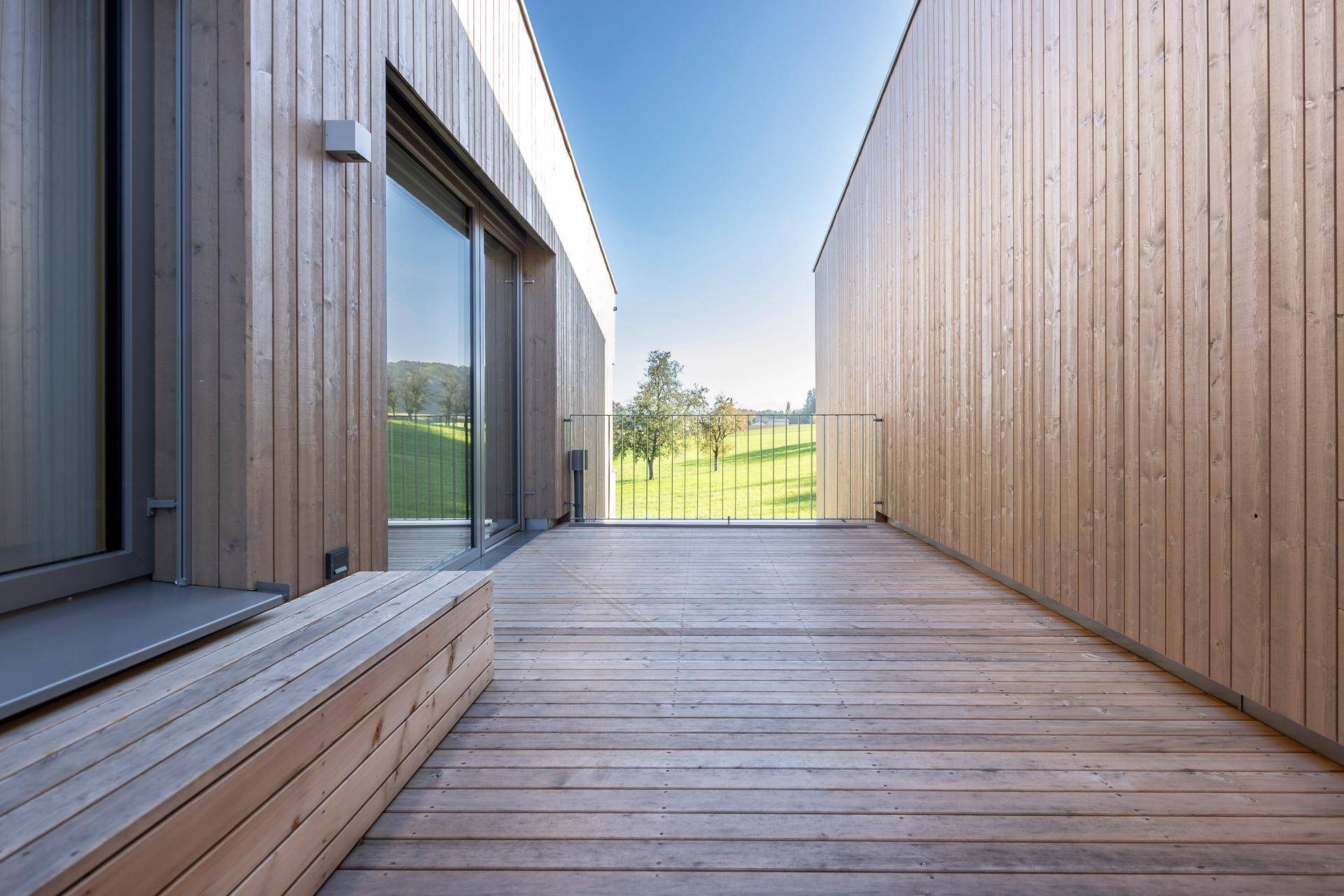 Große Holzterrasse mit Geländer und weitem Blick in die Natur.