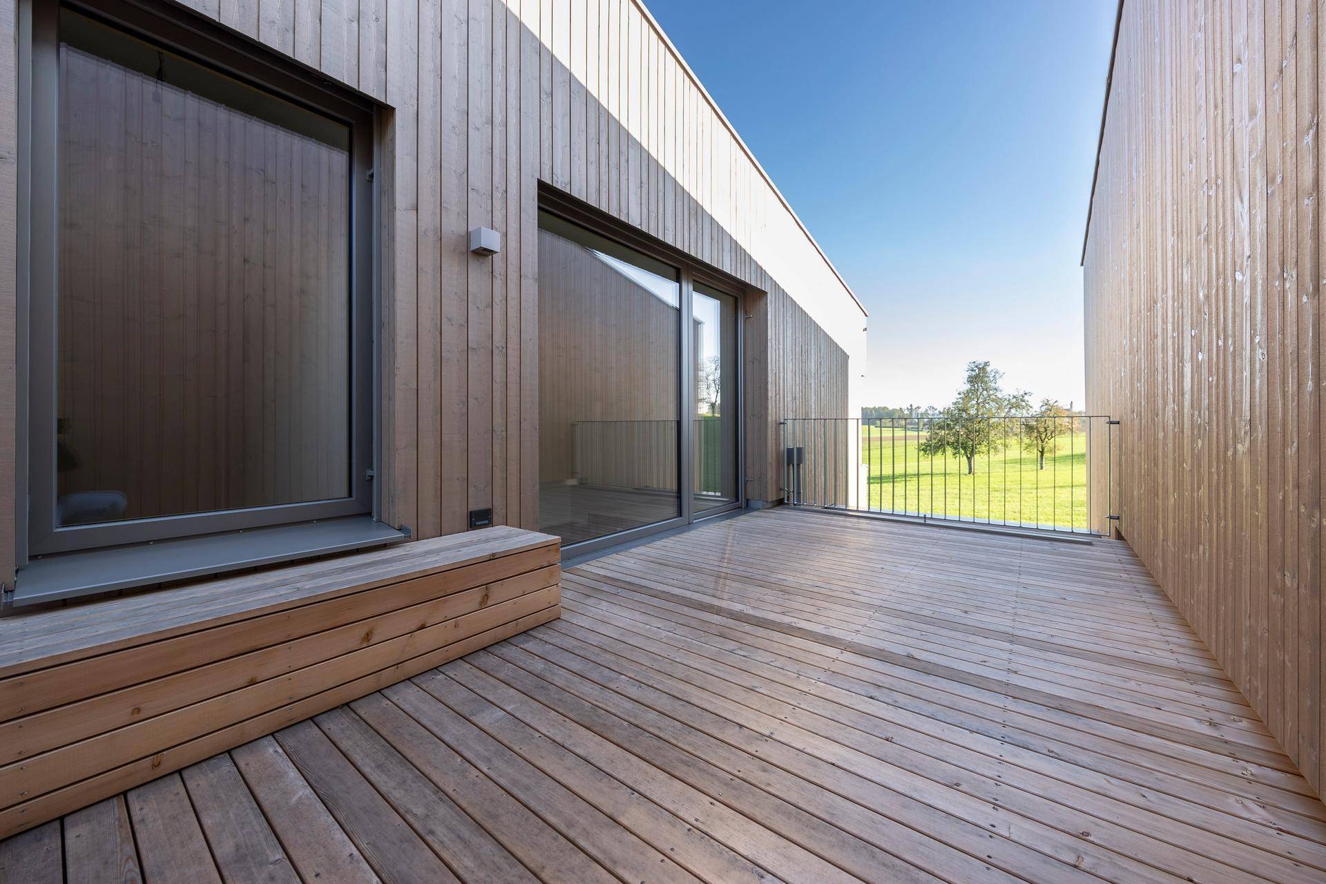 Geräumige Holzterrasse mit Schiebetür und weitem Blick ins Grüne.