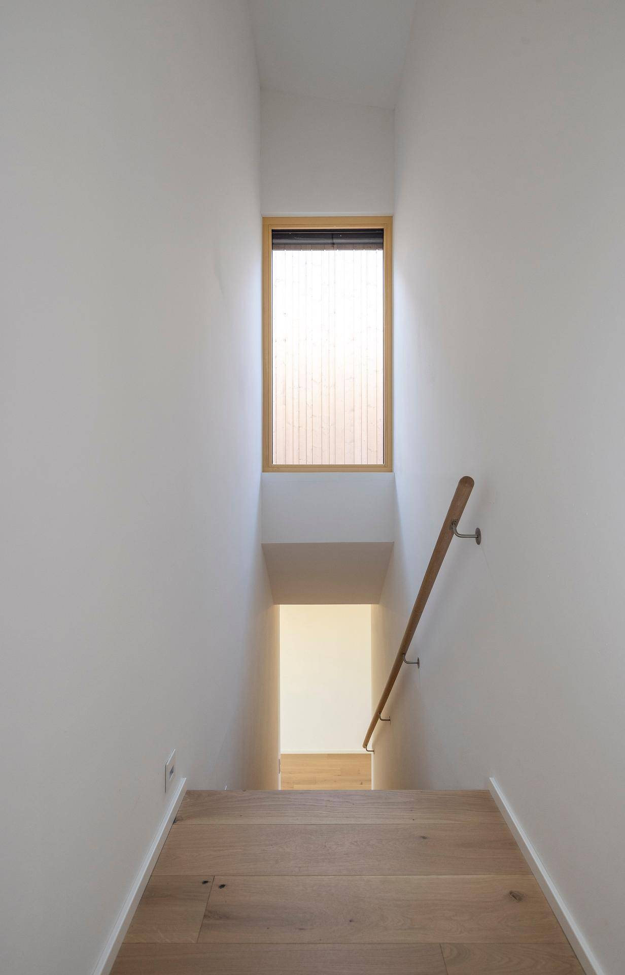 Treppenaufgang mit Holzstufen und Fenster für natürliches Licht.