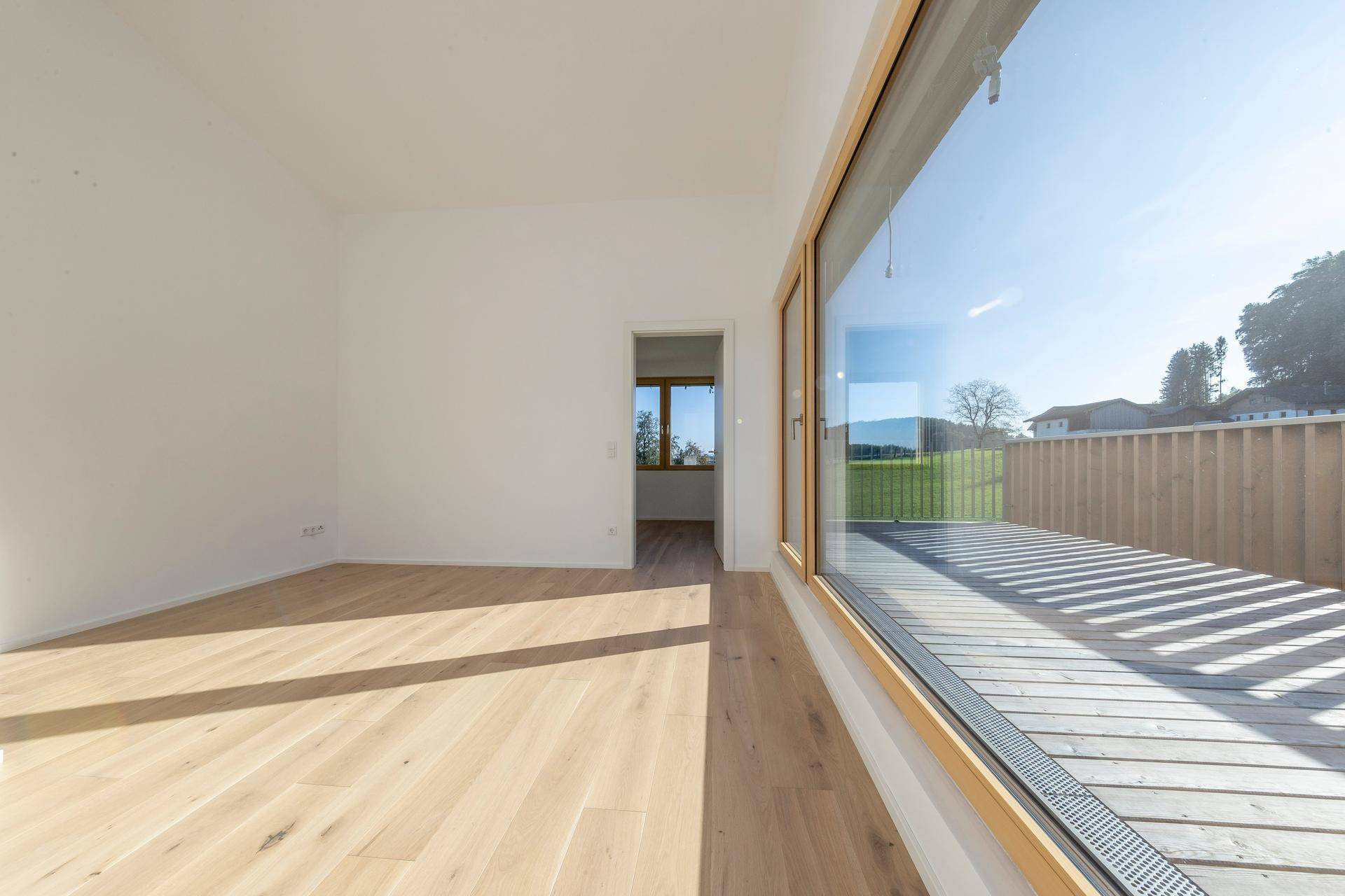 Heller Wohnraum mit Holzboden und Zugang zu einer Außenterrasse.