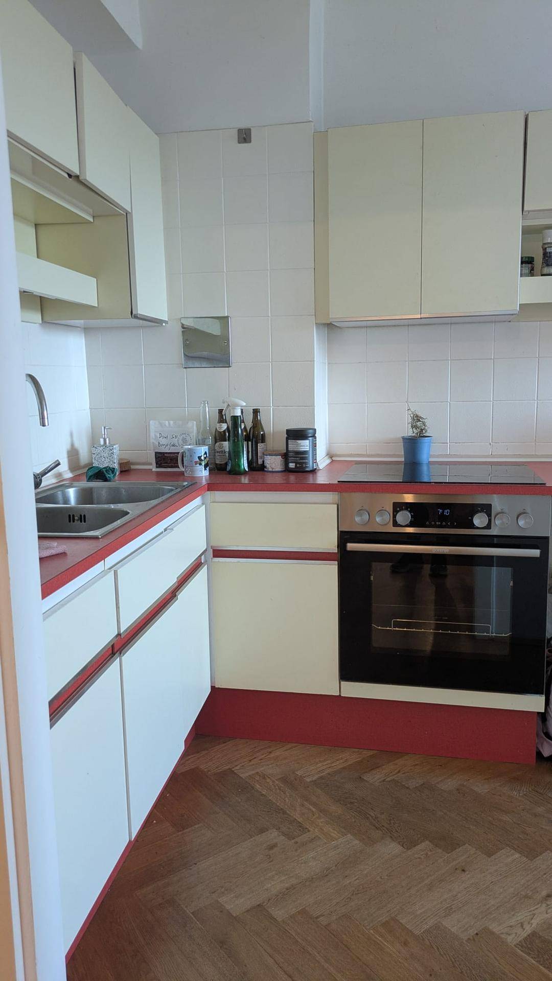 Detailansicht der Küche mit Backofen, Gasherd und roten Arbeitsplatten.