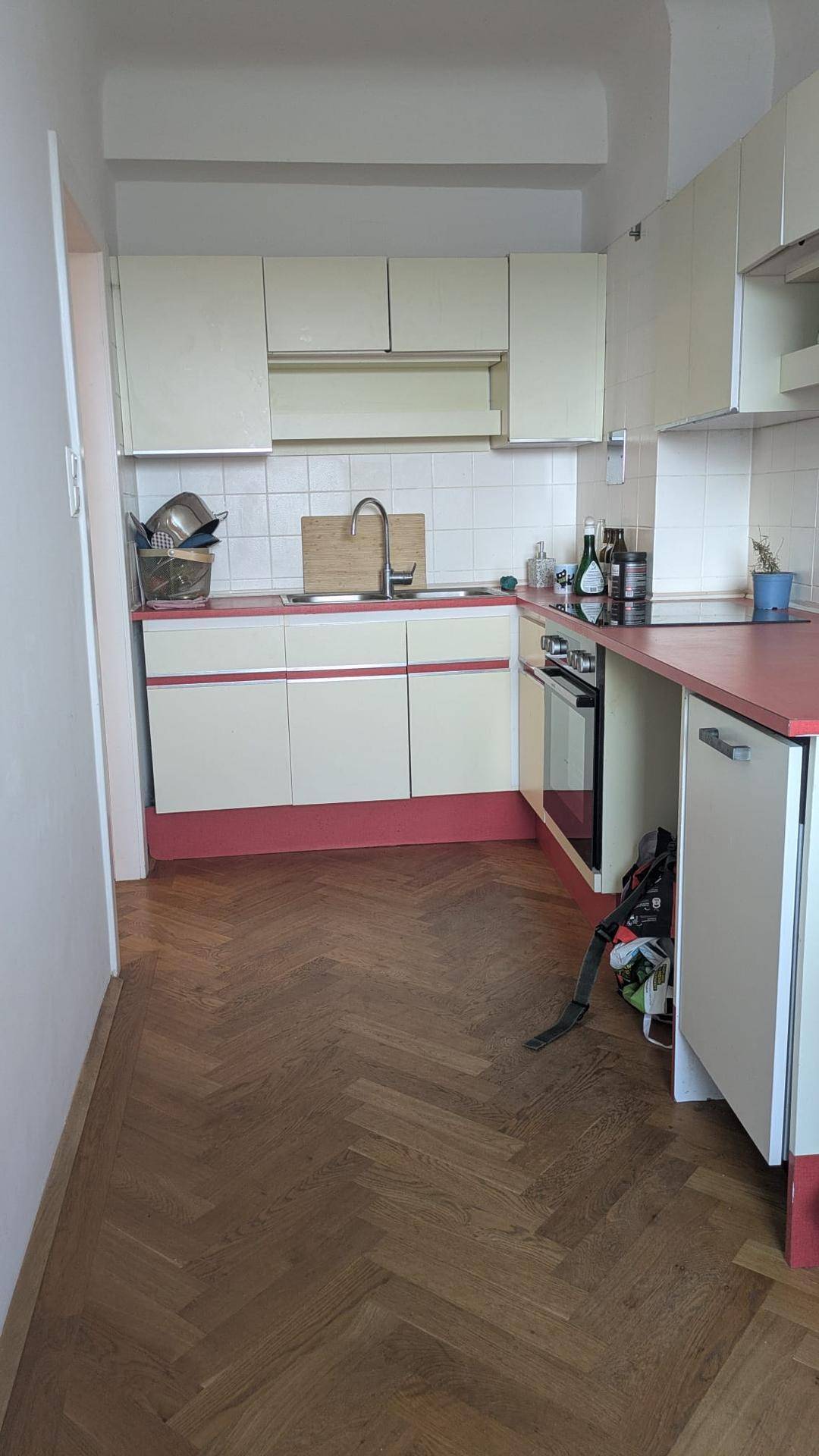 Küche mit weißen Oberschränken, roten Arbeitsplatten und Spülbecken.