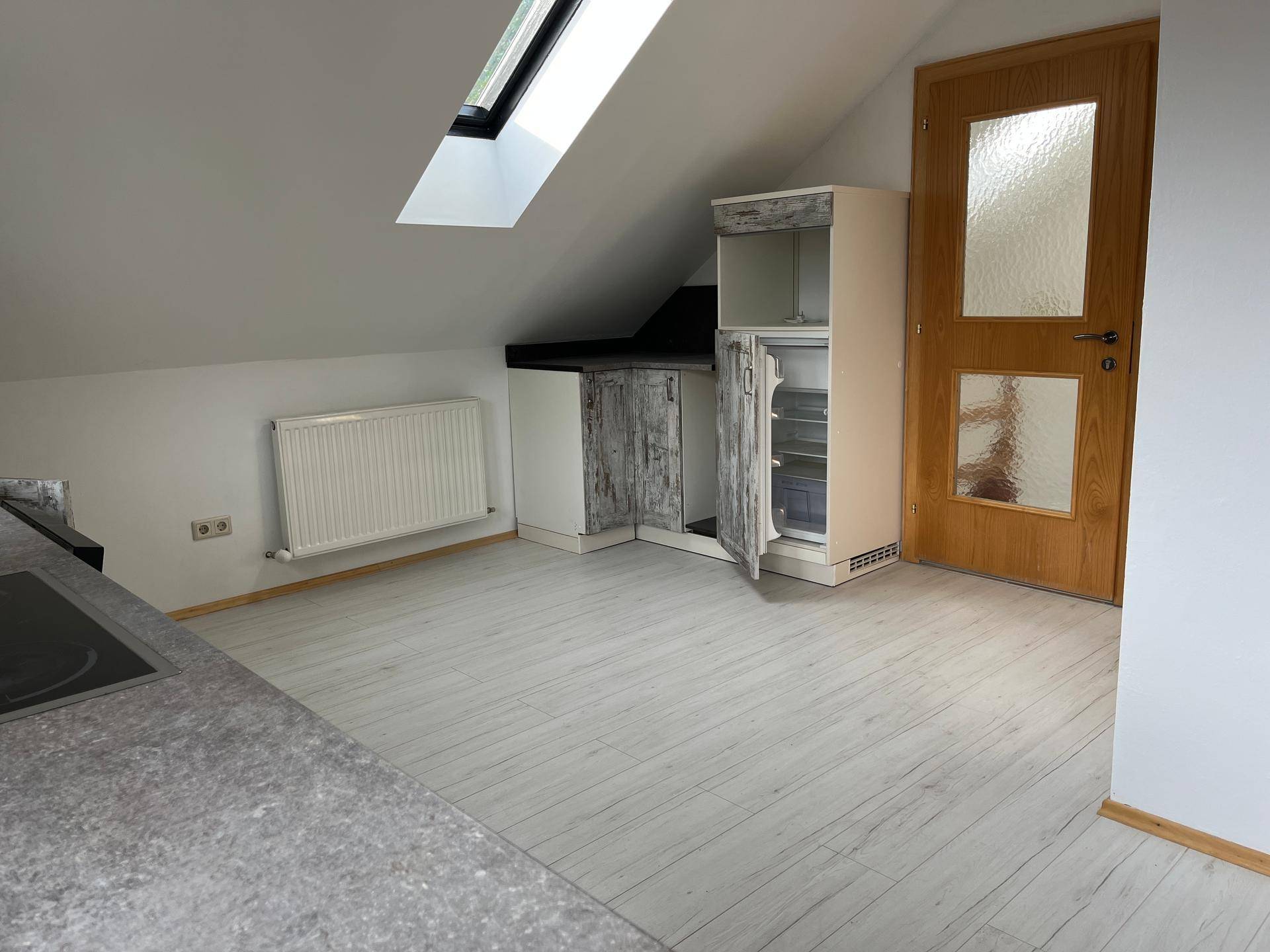 Kleine Küchenzeile im Dachgeschoss mit Arbeitsplatte, Kühlschrank und Dachfenster.