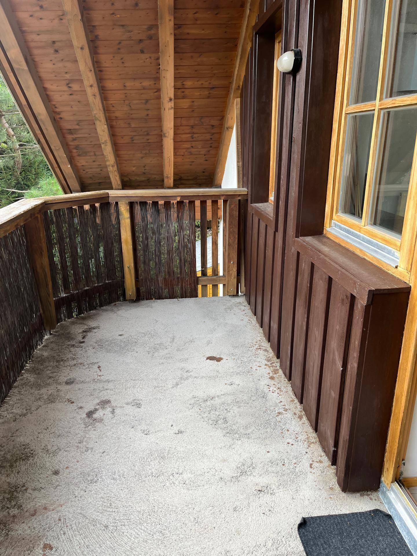 Kleiner Holzbalkon mit rustikalem Geländer, bietet einen geschützten Außenbereich.