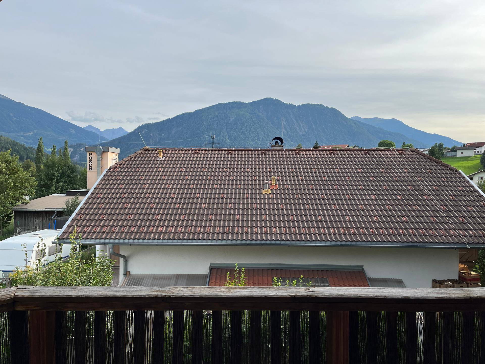 Panoramablick vom Balkon auf die umliegende Berglandschaft und Dächer der Nachbarschaft.
