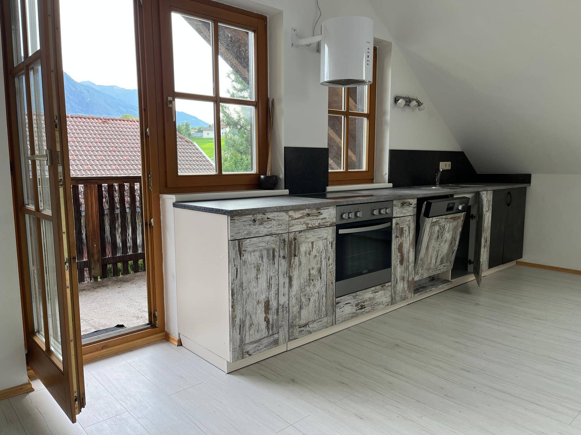 Funktionale Küche mit Einbaugeräten und Zugang zu einem Balkon, bietet Bergblick.