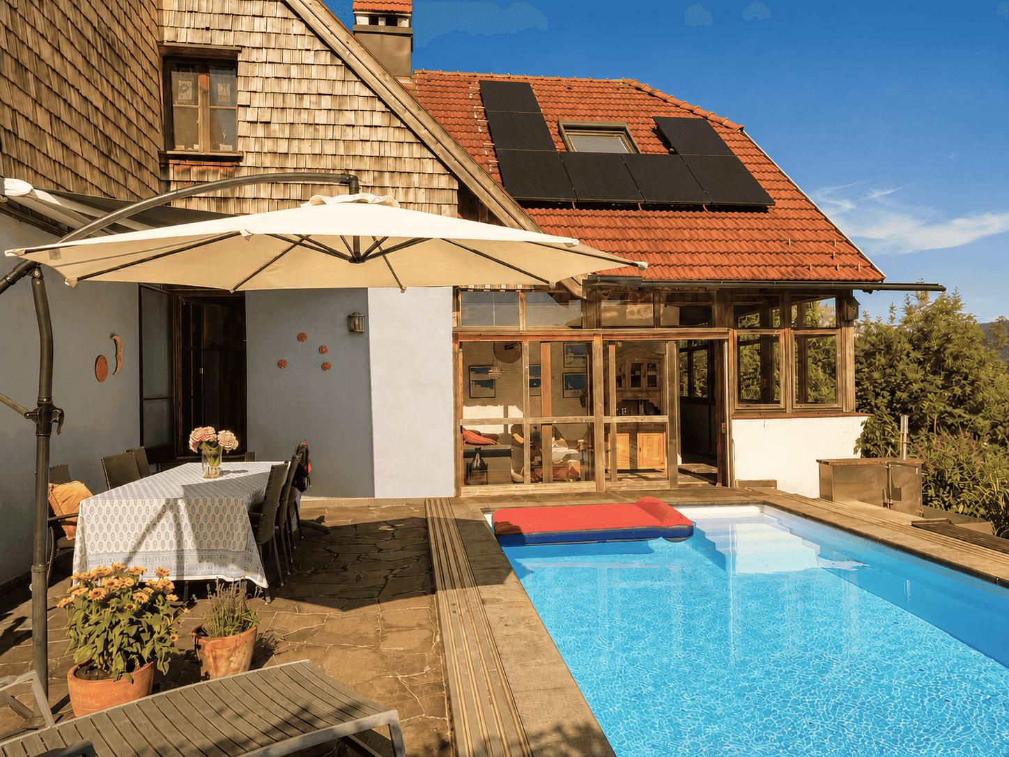 Sonnenterrasse mit Esstisch, Pool und Photovoltaikanlage auf dem Dach des Hauses mit Seeblick.