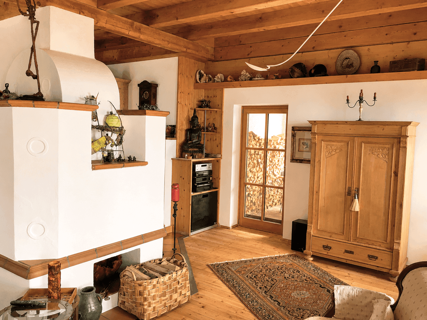 Gemütliches Wohnzimmer mit traditionellem Kachelofen, Holzdielenboden und rustikalen Holzmöbeln.