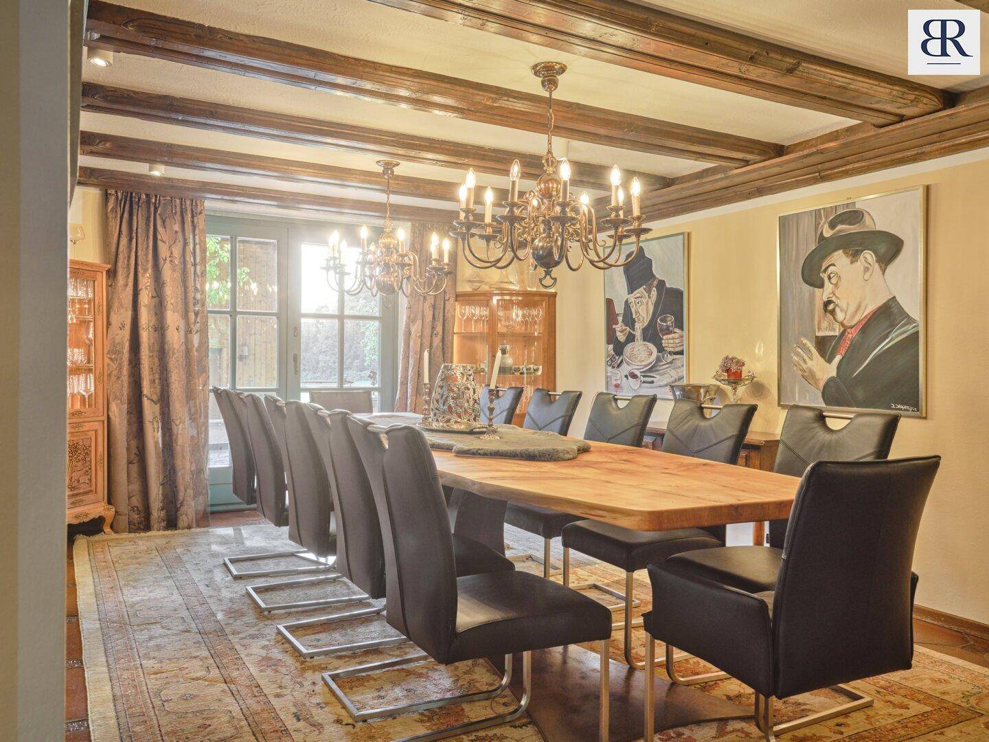 Elegantes Esszimmer mit großem Holztisch, Kronleuchtern und Zugang zum Außenbereich.
