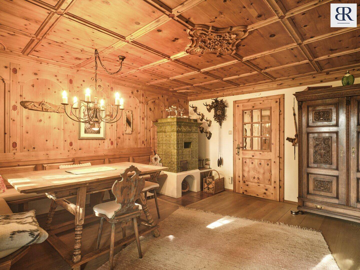 Traditionelle Stube mit Holztäfelung, Kachelofen und rustikalen Möbeln im alpinen Stil.