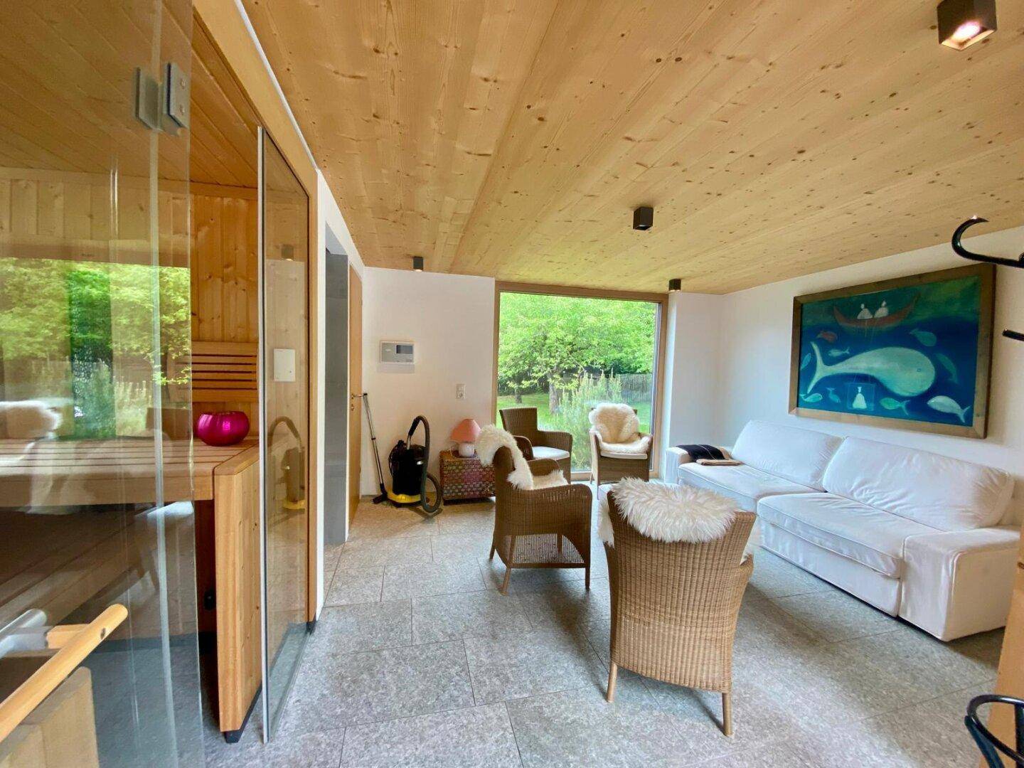 Entspannungsbereich mit Sauna und bequemen Sitzgelegenheiten, hell und modern gestaltet.