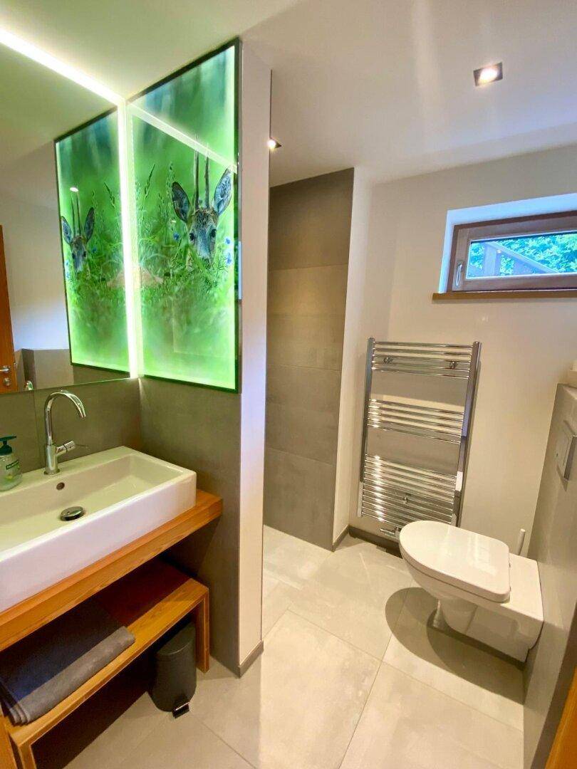 Modernes Badezimmer mit Waschtisch, Wand-WC und beheiztem Handtuchhalter.