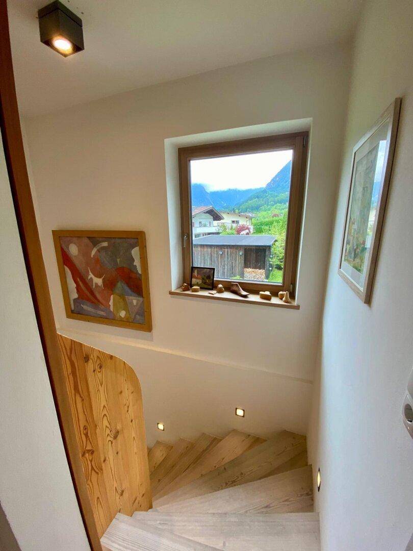 Heller Treppenaufgang mit Holzstufen und Fenster, bietet einen Blick auf die Umgebung.