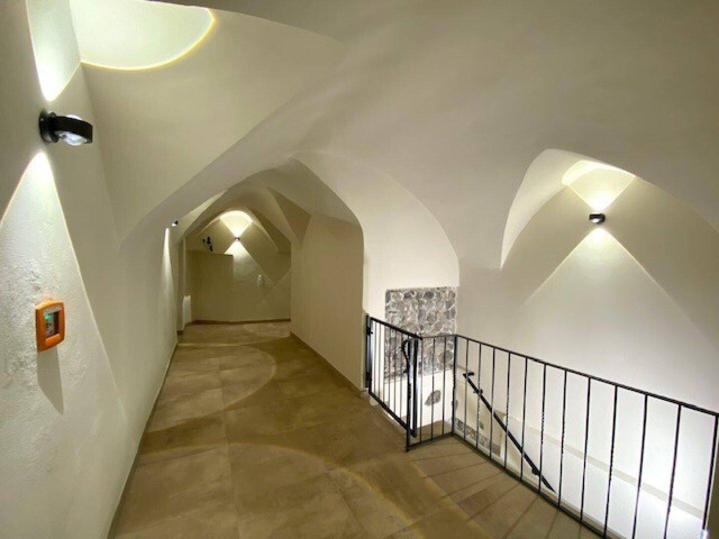 Historischer Flur mit beeindruckenden Gewölbedecken, Fliesenboden und stilvoller Beleuchtung.