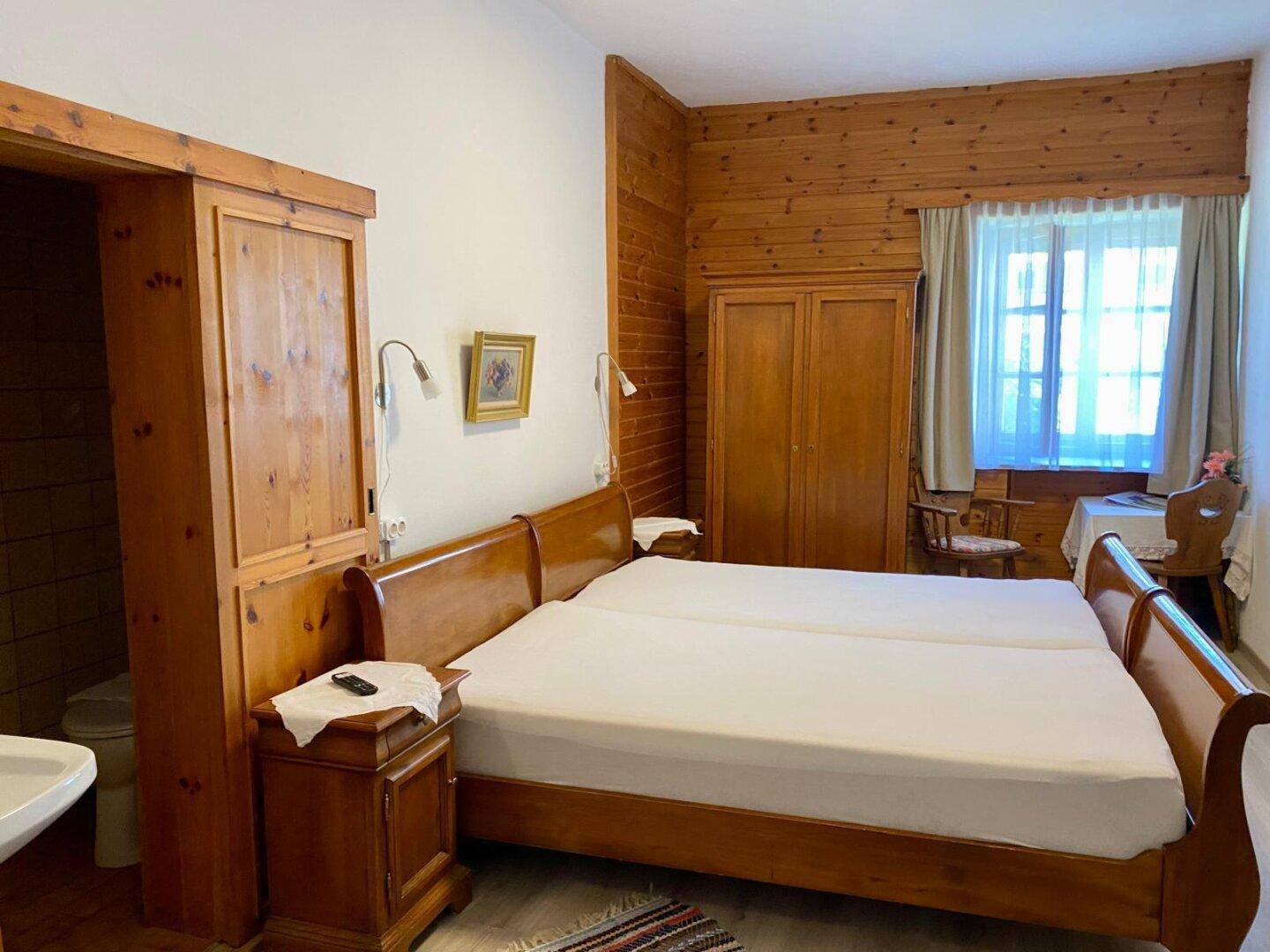 Gemütliches Schlafzimmer mit Holzvertäfelung, zwei Einzelbetten und einem kleinen Badezimmerzugang.