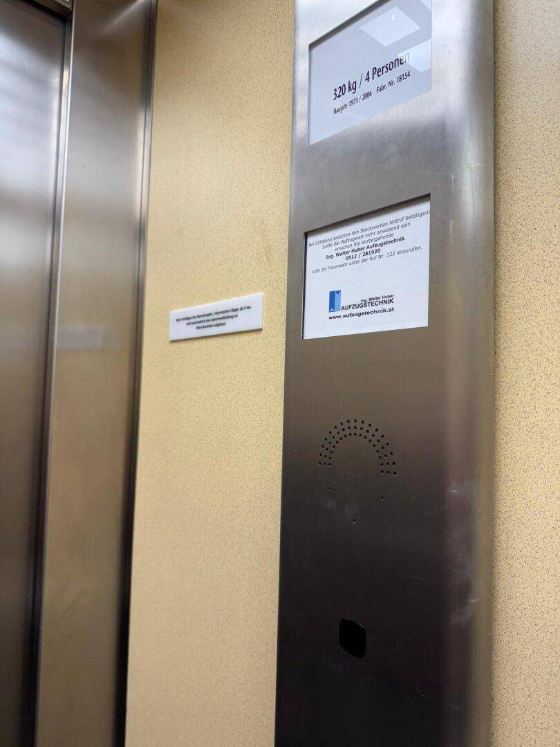Moderner Aufzug im Gebäude mit Edelstahlverkleidung und Informationsanzeigen.