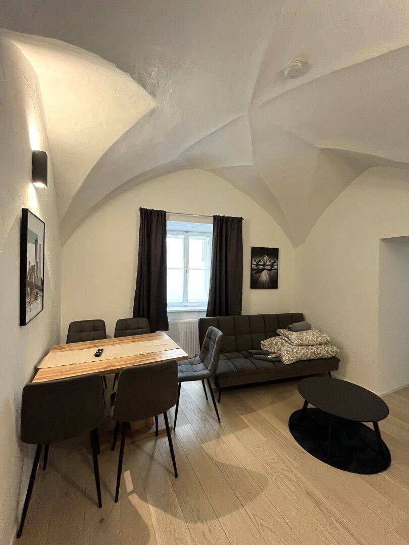 Gemütlicher Wohn- und Essbereich mit Holztisch, Sofa und charakteristischer Gewölbedecke.