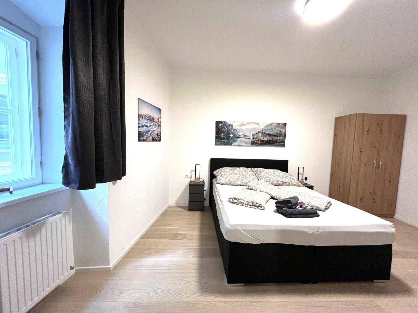 Helles Schlafzimmer mit Doppelbett, Nachttischen und Kleiderschrank.
