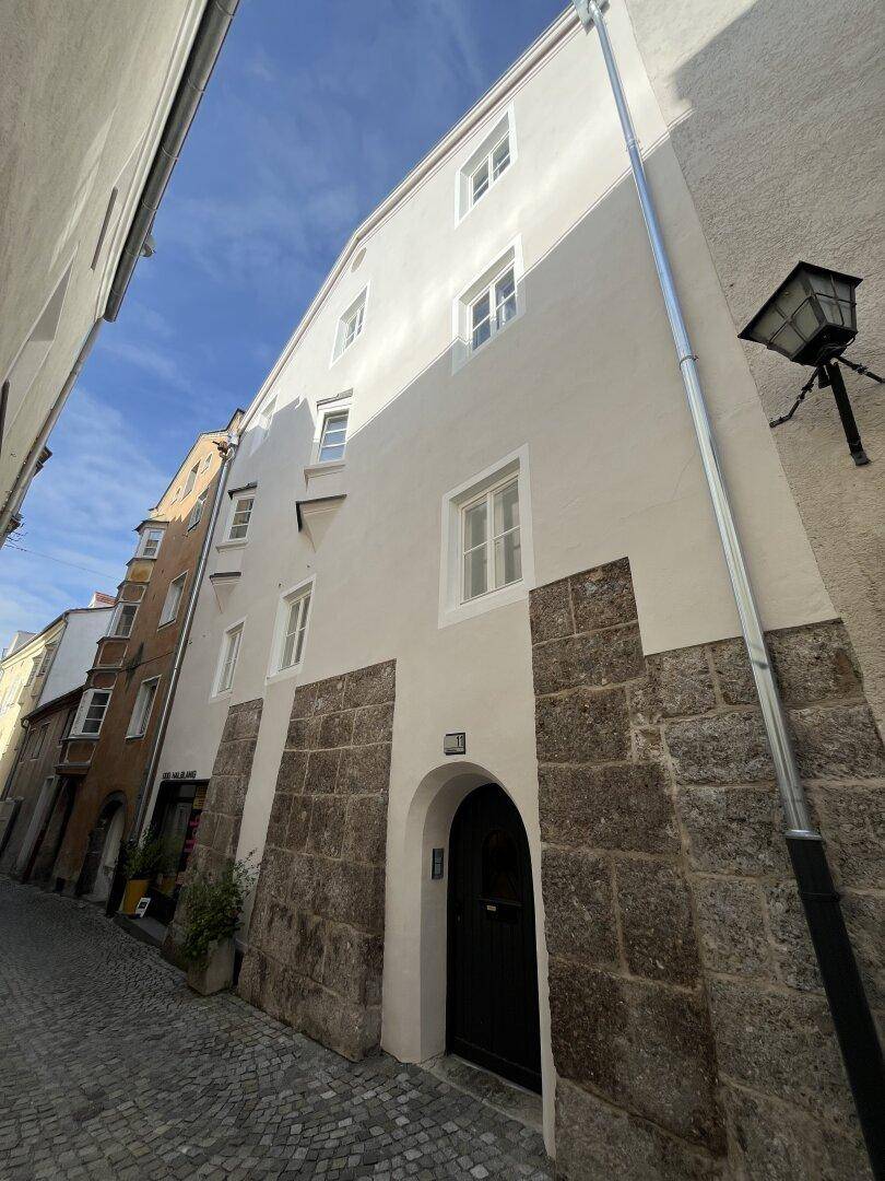 Historische Fassade eines Gebäudes in einer engen Gasse mit Kopfsteinpflaster.