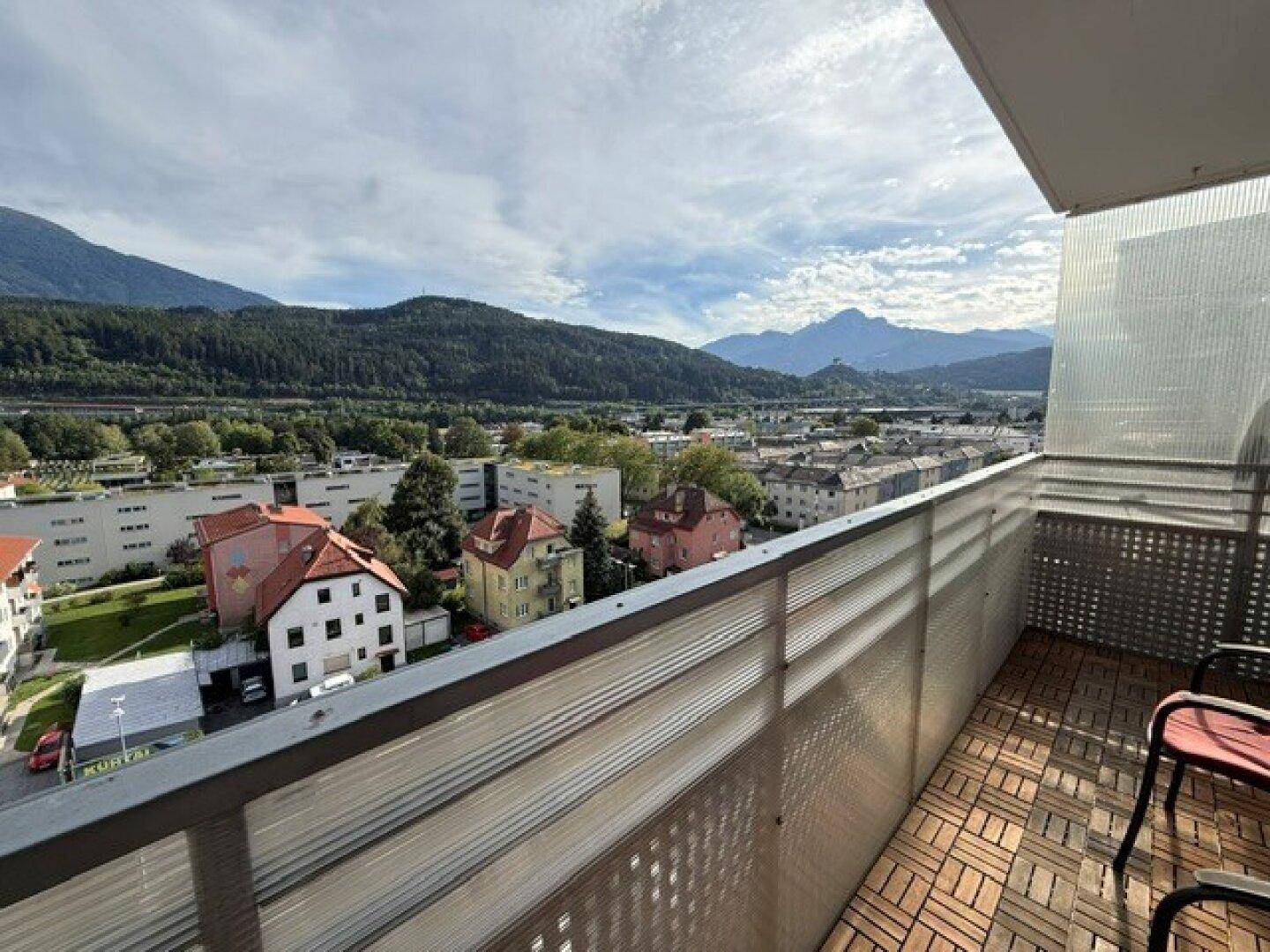 Geräumiger Balkon mit Holzboden und weitem Blick über die Stadt und die umliegende Berglandschaft.