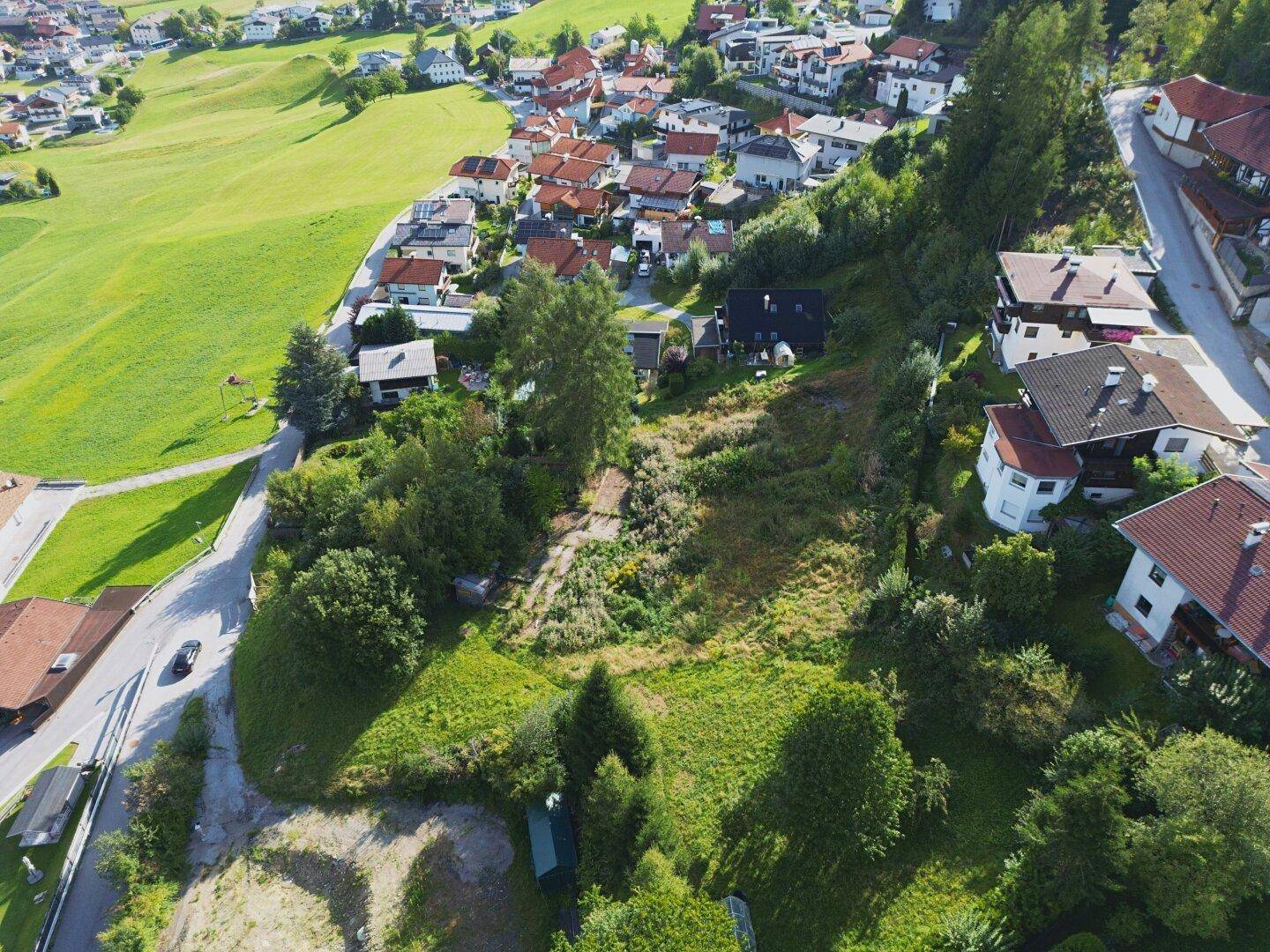 Weitläufige Luftaufnahme des Grundstücks mit umliegenden Häusern und Bergblick im Hintergrund.