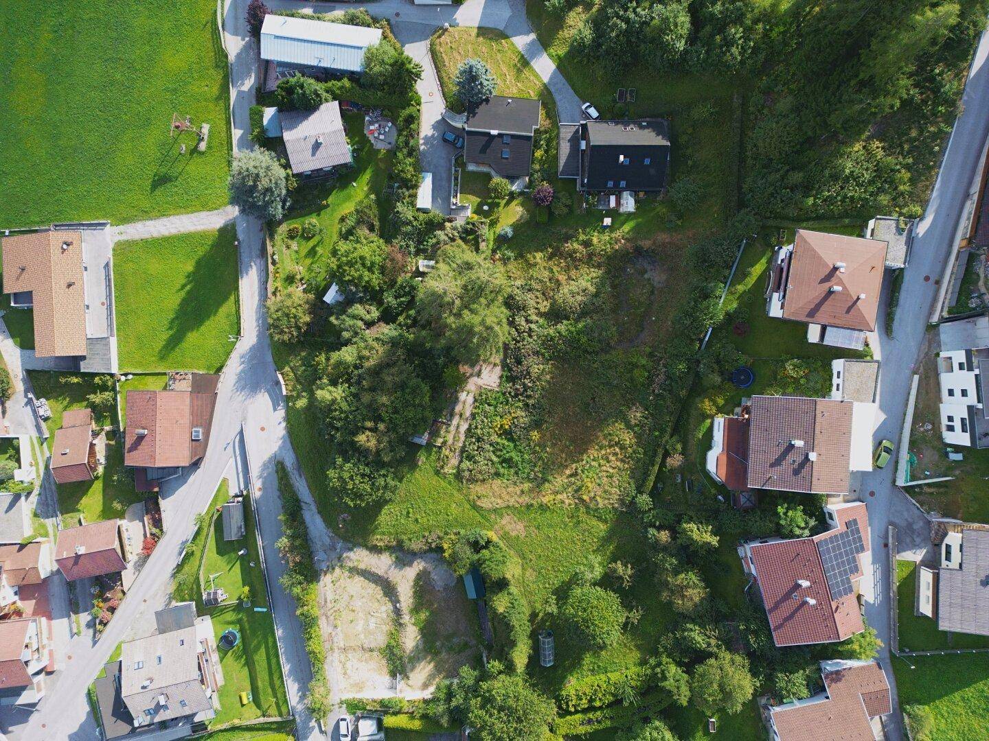 Direkte Draufsicht auf das unbebaute Grundstück, umgeben von Gärten und Wohngebäuden.