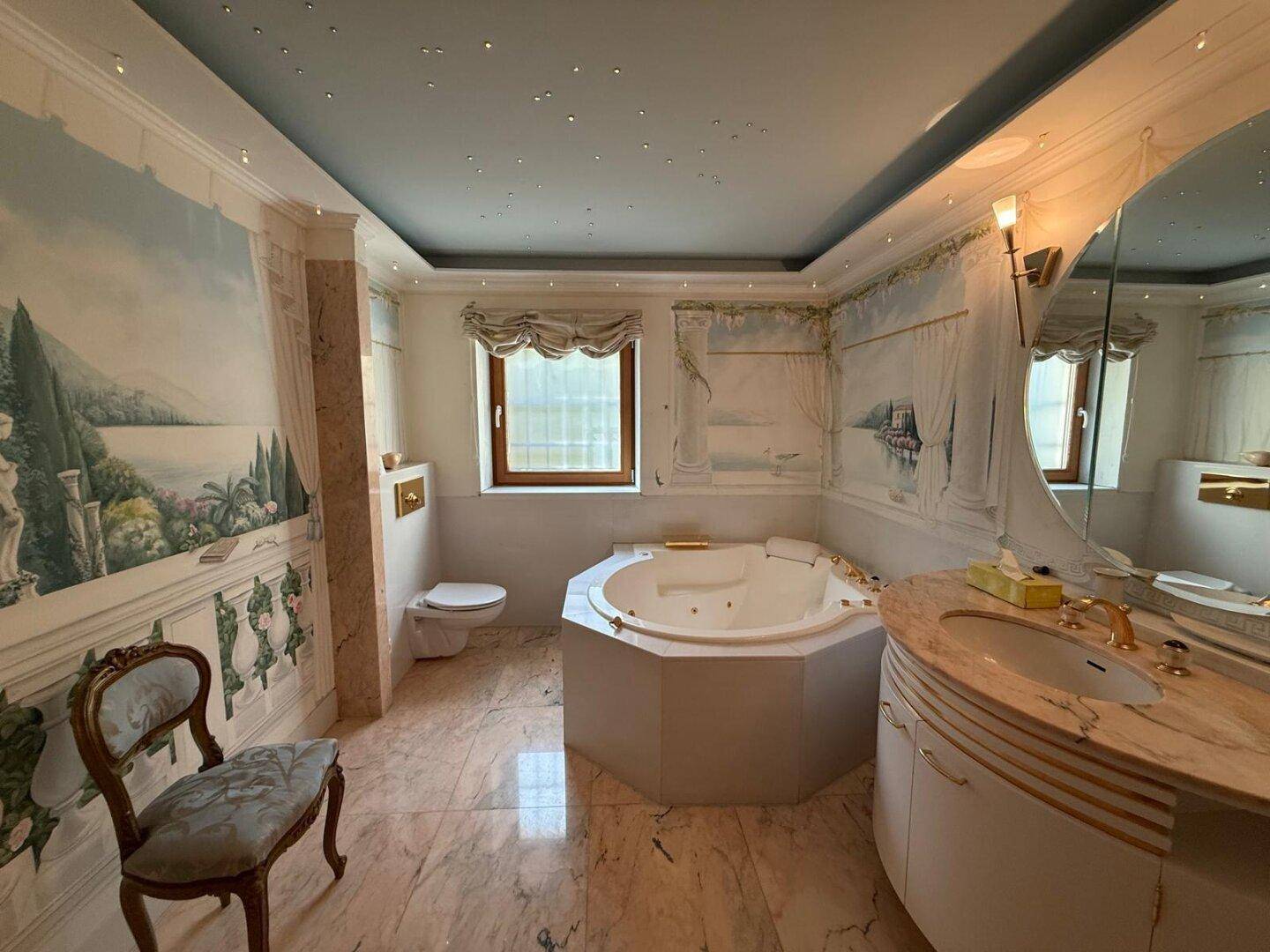 Elegantes Badezimmer mit Whirlpool, Marmorwaschtisch und dekorativen Wandmalereien.