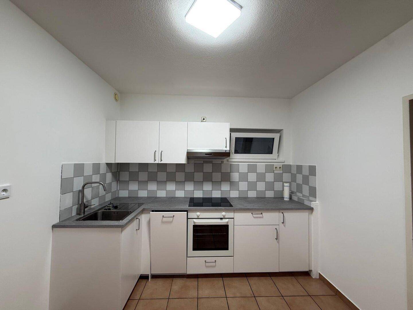 Kompakte Einbauküche mit weißen Fronten, integriertem Backofen und Kochfeld, ideal für den täglichen Gebrauch.