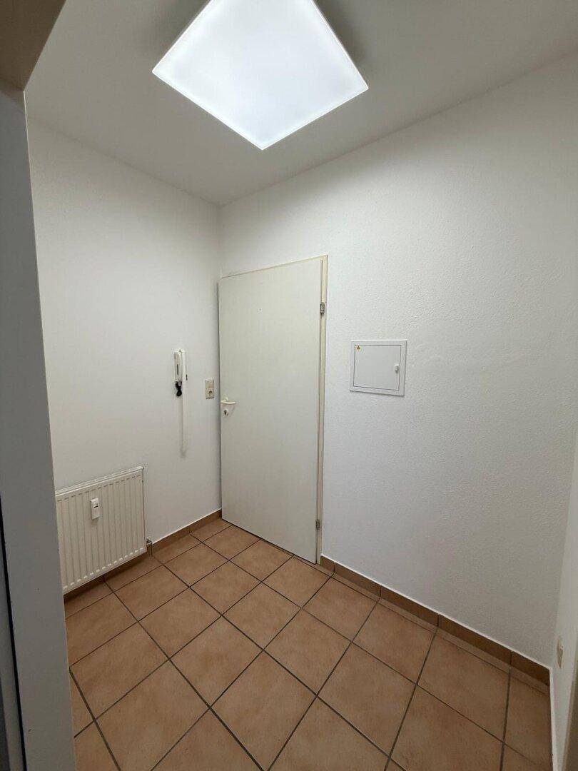 Eingangsbereich mit Fliesenboden, weißer Tür und Gegensprechanlage, bietet einen freundlichen Empfang.