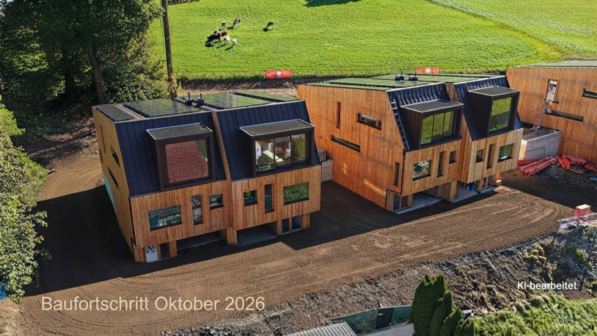 Luftaufnahme von zwei modernen Holzhäusern im Bau mit Gründach und ländlicher Umgebung.