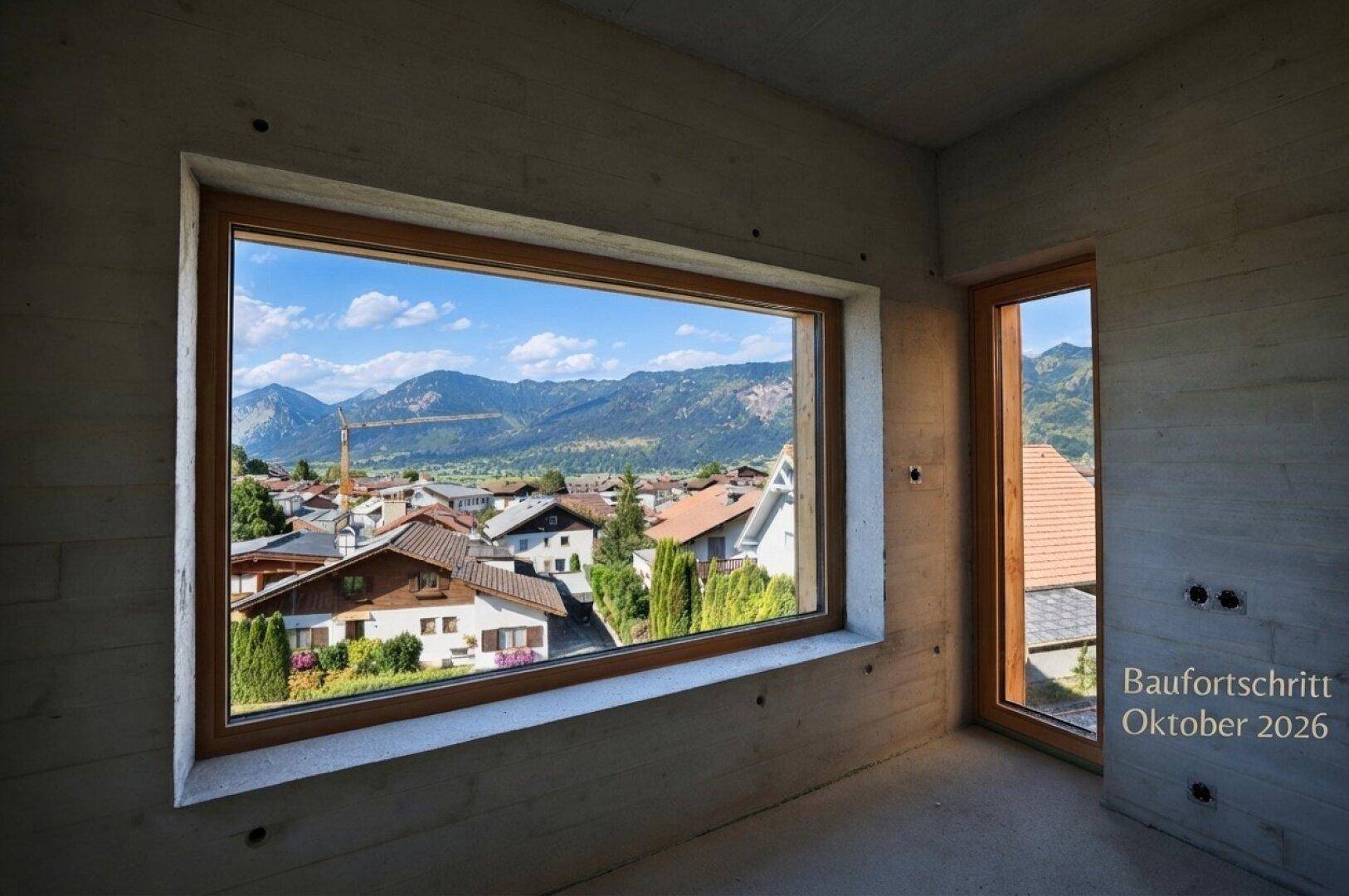 Unfertiger Raum mit Betonwänden und weitem Blick auf ein Dorf und die umliegenden Berge.