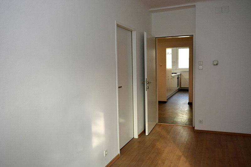 Unmöblierter Raum mit Laminatboden und Zugang zu einer Küche, ideal für flexible Nutzung.
