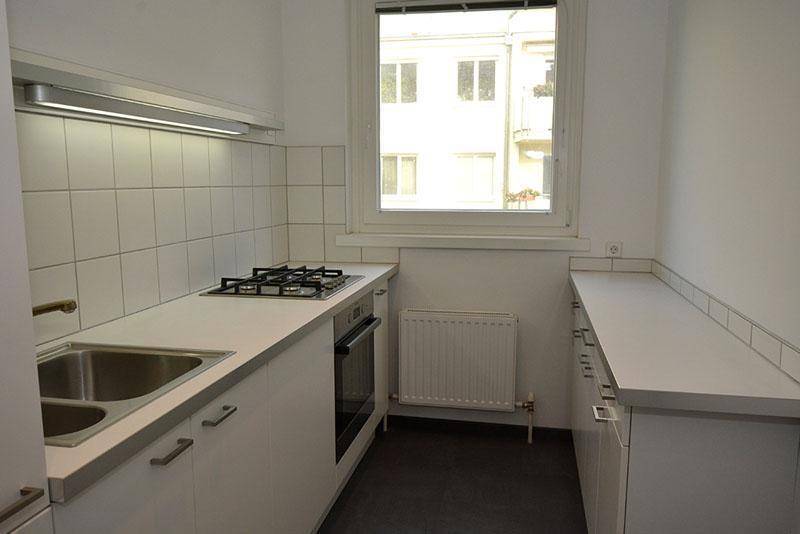 Funktionale Küche mit weißen Schränken, Gasherd und Fenster, ideal für den täglichen Gebrauch.