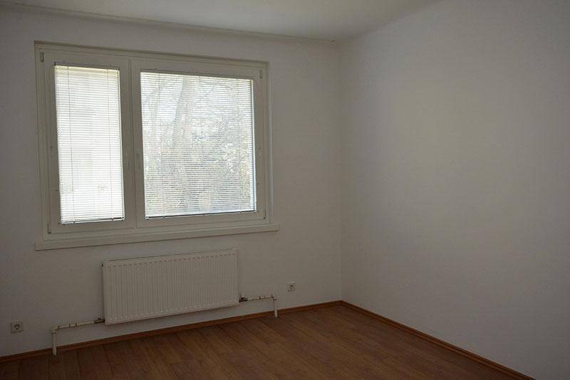 Heller, unmöblierter Raum mit Laminatboden, großem Fenster und Heizkörper, bereit zur Einrichtung.