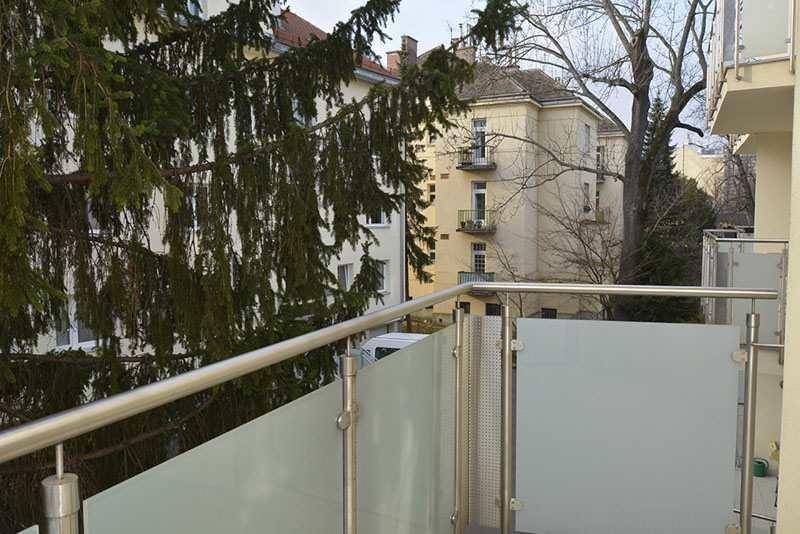 Moderner Balkon mit Glasbrüstung und Edelstahlgeländer, bietet einen Blick auf die Umgebung.
