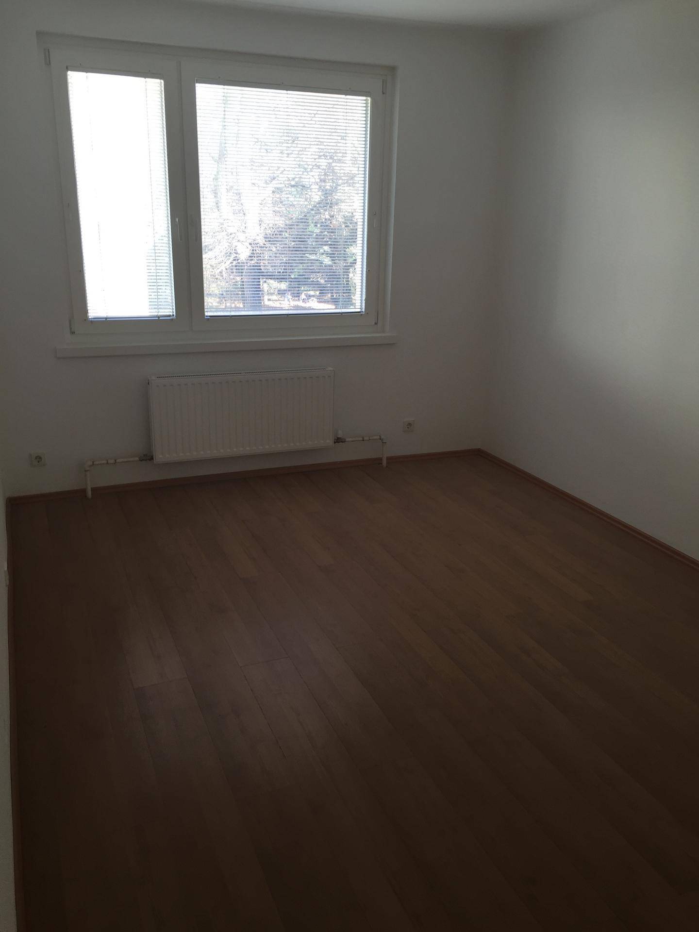 Heller, unmöblierter Raum mit Laminatboden und Fenster, bereit für individuelle Nutzung.