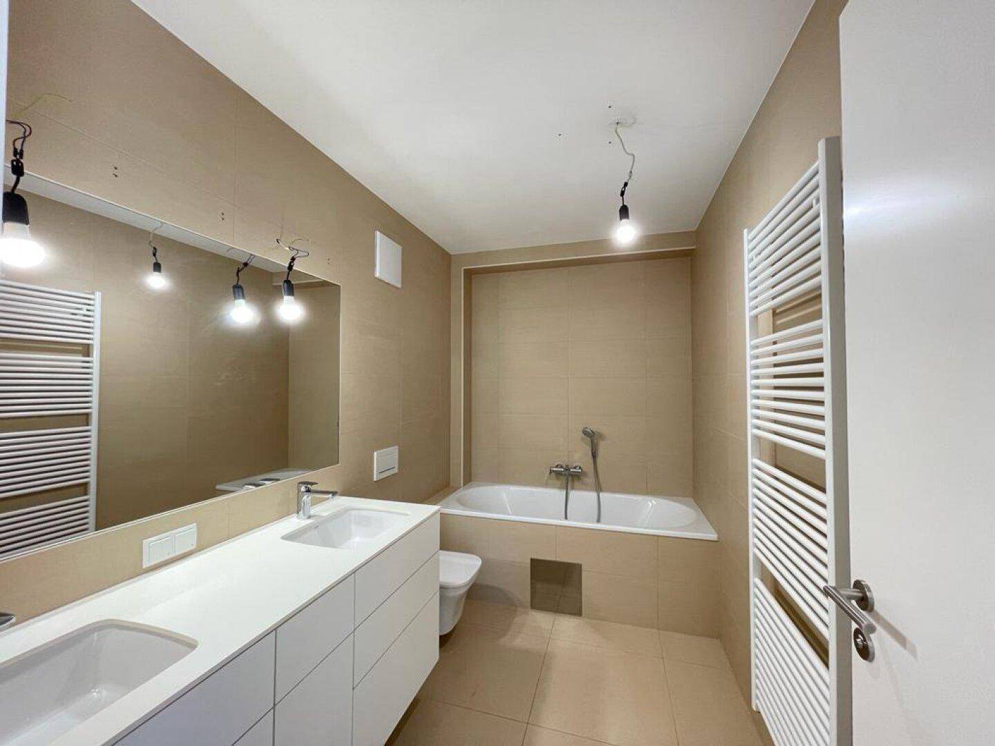Modernes Badezimmer mit Doppelwaschbecken, Badewanne und beheiztem Handtuchhalter.