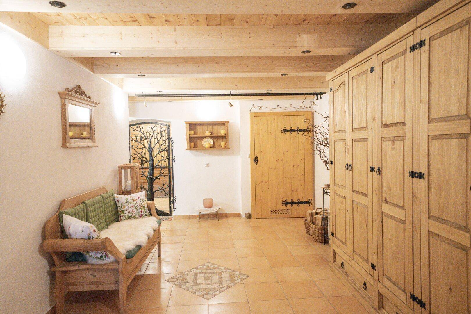 Gemütlicher Eingangsbereich mit Holzmöbeln, gefliestem Boden und sichtbaren Deckenbalken.
