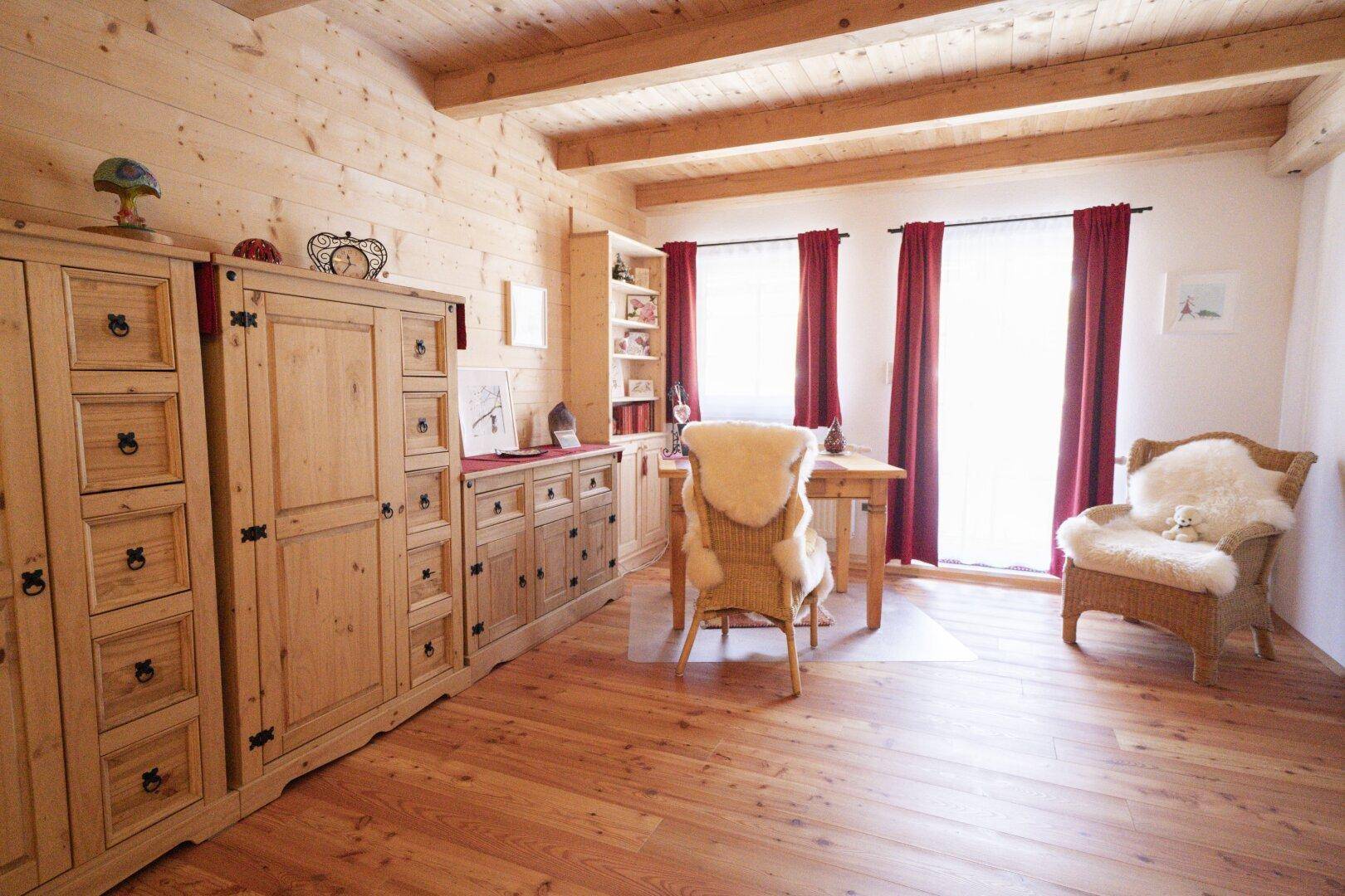 Helles Schlafzimmer mit Holzboden, traditionellen Holzmöbeln und gemütlichen Fellsesseln.