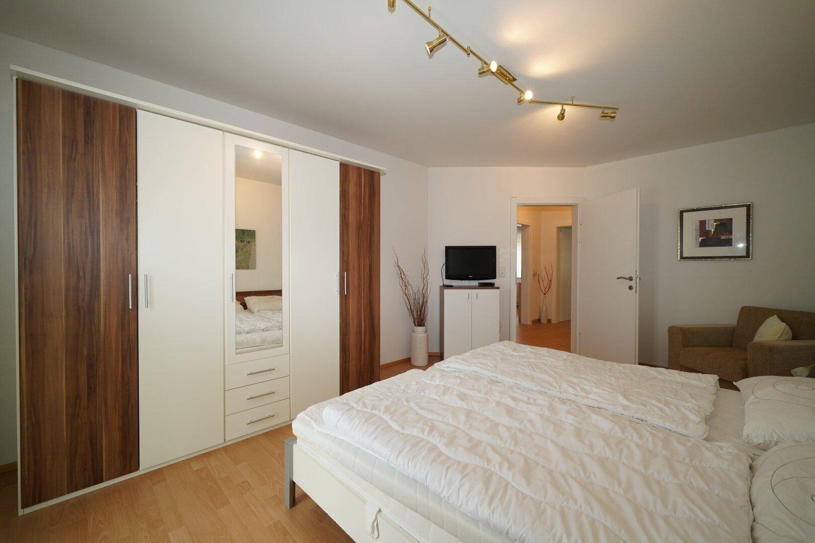 Gemütliches Schlafzimmer mit großem Bett, Einbauschränken und hellem Laminatboden.