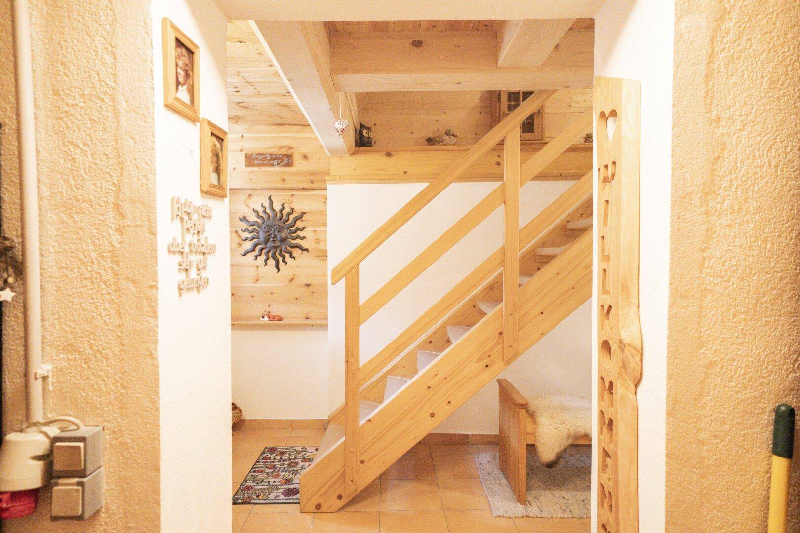 Heller Treppenaufgang mit Holzgeländer und traditioneller Dekoration in einem rustikalen Ambiente.
