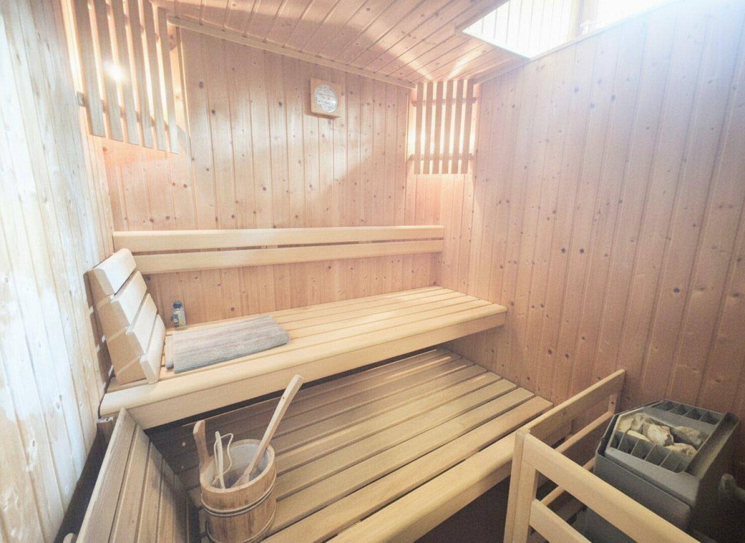 Helle Holzsauna mit mehreren Bänken und traditionellem Saunaofen.