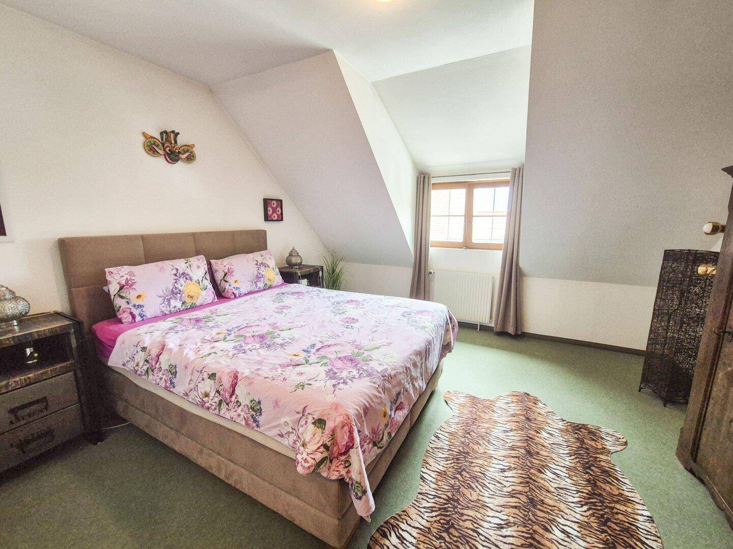 Schlafzimmer im Dachgeschoss mit schrägen Wänden, Teppichboden und Doppelbett.