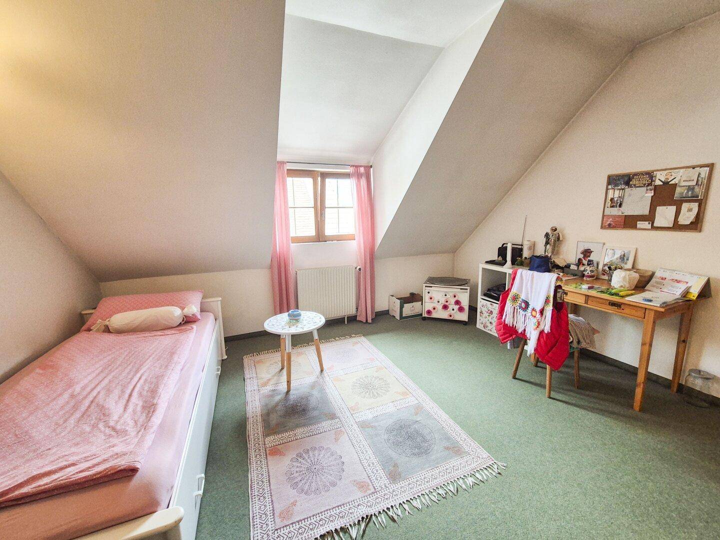 Kinderzimmer oder Gästezimmer im Dachgeschoss mit Einzelbett und Schreibtisch.